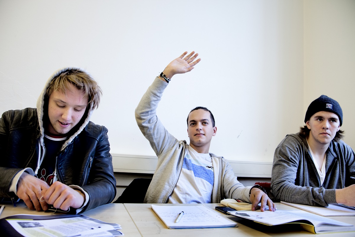 Kille räcker upp handen i klassrummet