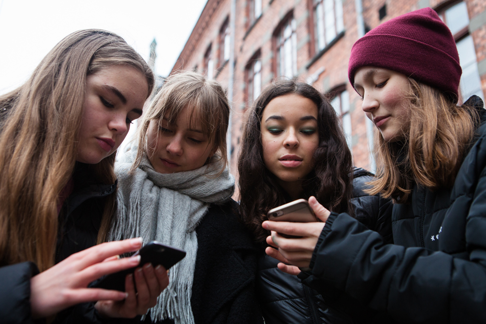 Fyra tjejer tittar i mobilen
